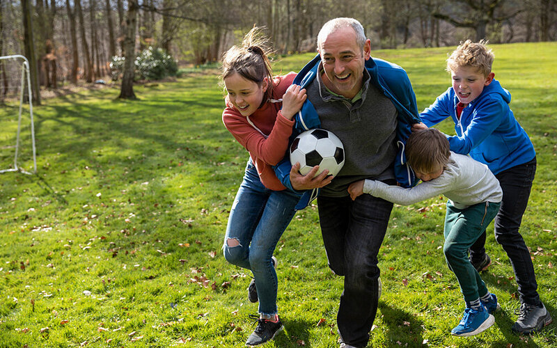 Opa spielt mit den Enkelkindern mit einem Ball. Das stärkt das Immunsystem, in dem Leukozyten eine wichtige Funktion übernehmen.