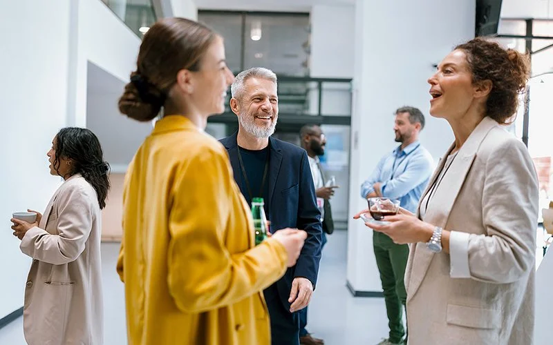 Eine kleine Gruppe von Frauen und Männern führt in der Konferenzpause ein lockeres Gespräch. Es bringt sie auch zum Lachen.
