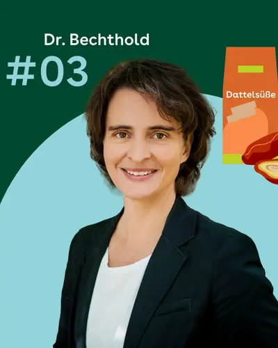 Dr. Angela Bechthold steht vor einem grünen Hintergrund. Rechtes daneben sind eine orangefarbene Verpackung mit der Aufschrift Dattelsüße und mehrere halbierte Datteln zu sehen.