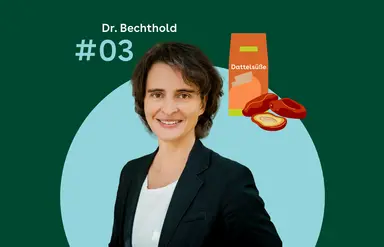 Dr. Angela Bechthold steht vor einem grünen Hintergrund. Rechtes daneben sind eine orangefarbene Verpackung mit der Aufschrift Dattelsüße und mehrere halbierte Datteln zu sehen.