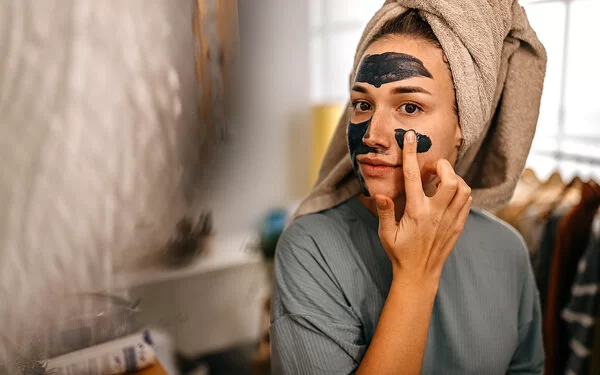 Junge Frau legt eine selbstgemachte Gesichtsmaske auf.