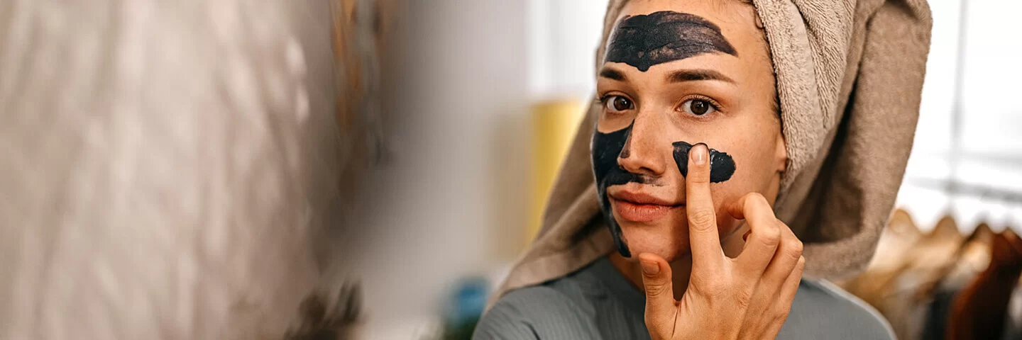 Junge Frau legt eine selbstgemachte Gesichtsmaske auf.