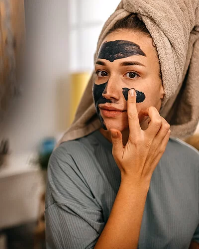 Junge Frau legt eine selbstgemachte Gesichtsmaske auf.