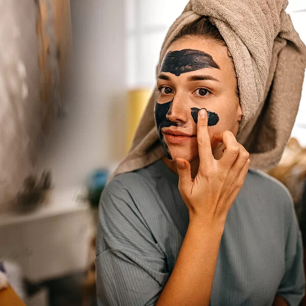 Junge Frau legt eine selbstgemachte Gesichtsmaske auf.