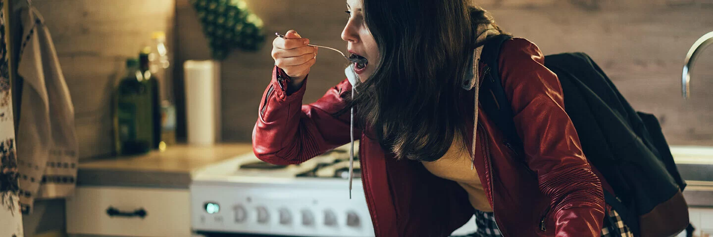 Eine Studentin hat keine Zeit zum Kochen und isst gehetzt Müsli.