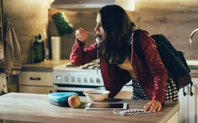 Eine Studentin hat keine Zeit zum Kochen und isst gehetzt Müsli.