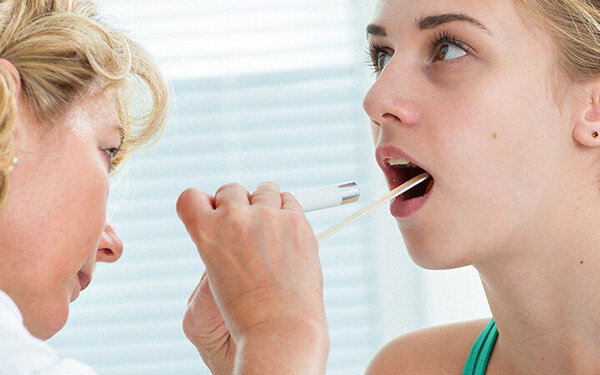 Eine Ärztin untersucht eine Frau auf Mundhöhlenkrebs.