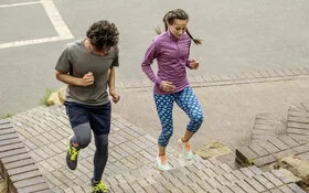 Eine Frau und ein Mann joggen eine Treppe hoch