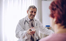 Ein Arzt zeigt einer Patientin Tabletten und erklärt den Placeboeffekt.