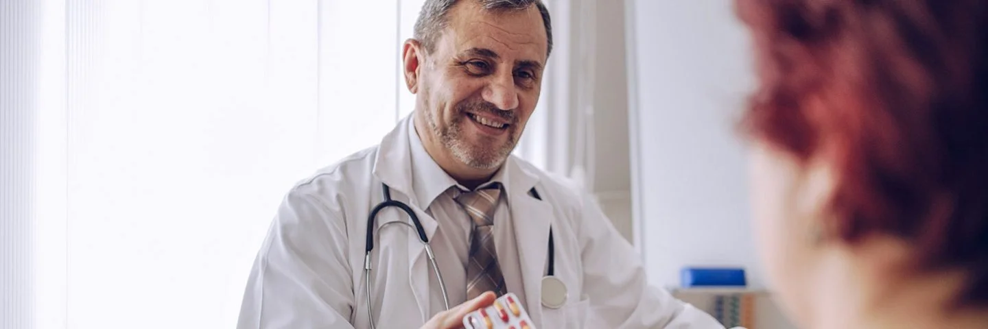 Ein Arzt zeigt einer Patientin Tabletten und erklärt den Placeboeffekt.
