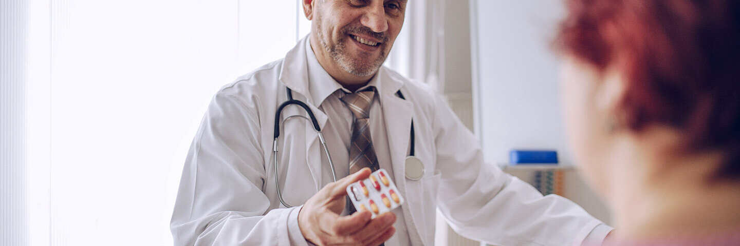 Ein Arzt zeigt einer Patientin Tabletten und erklärt den Placeboeffekt.