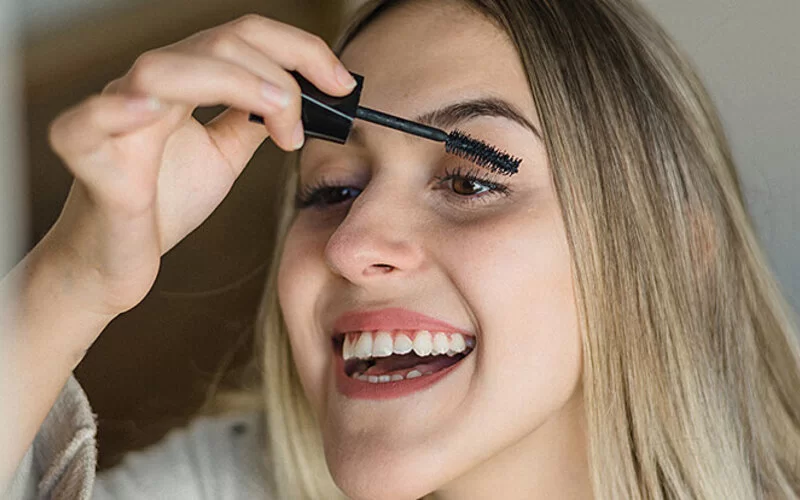 Eine Frau gibt mit einem Wattestäbchen Wimpernserum auf ihre Wimpern