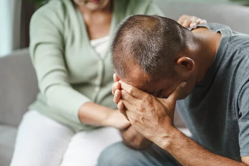 Ein nachdenklich wirkender, junger Mann sitzt auf einer Bank. Der Familiencoach Depression hilft dabei, den Alltag mit einem depressiv erkrankten Menschen besser zu bewältigen.