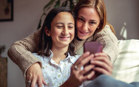 Eine Mutter schaut gemeinsam mit Ihrer Tochter etwas auf dem Smartphone an
