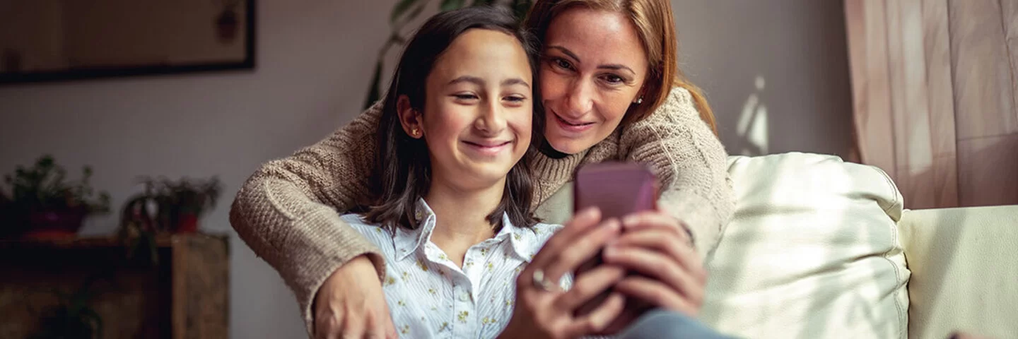 Eine Mutter schaut gemeinsam mit Ihrer Tochter etwas auf dem Smartphone an