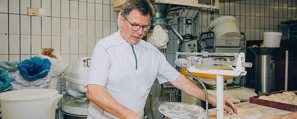 Der Bäckermeister Stefan Steeg bereitet auf einer Arbeitsfläche seiner Backstube Brotteiglinge zum Backen vor.
