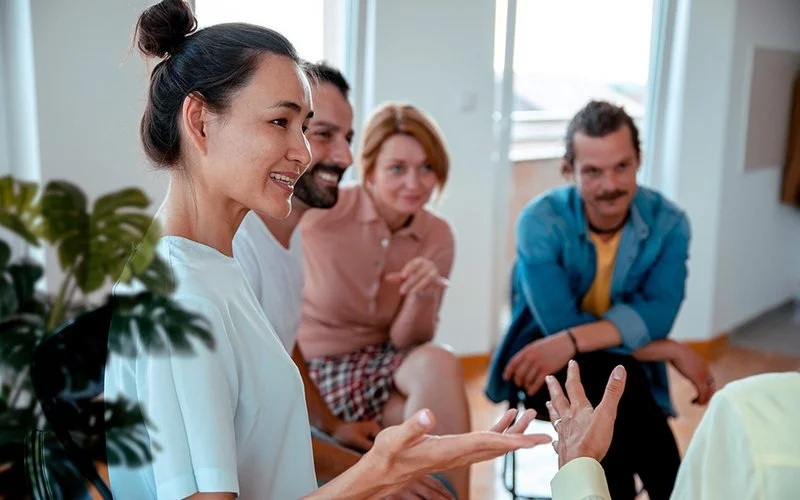 Eine Gruppe von Frauen und Männern sitzt im Kreis und unterhält sich.