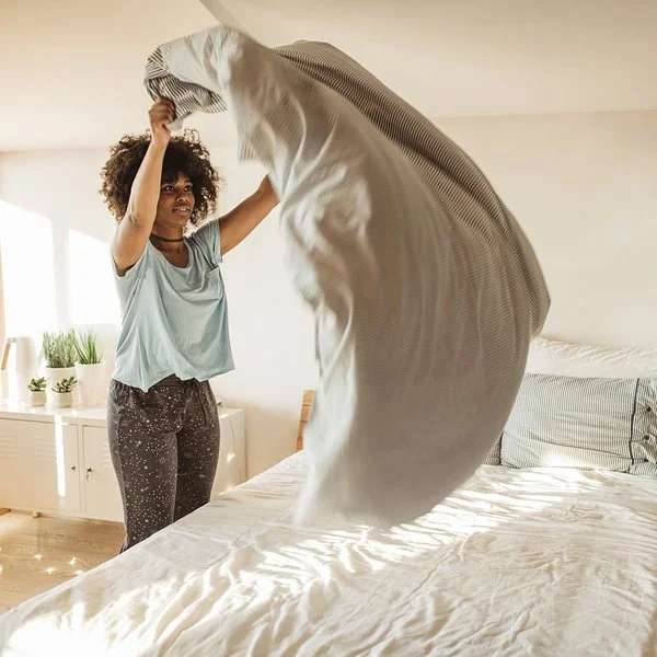 Eine Frau bezieht frisch gewaschene Bettwäsche.