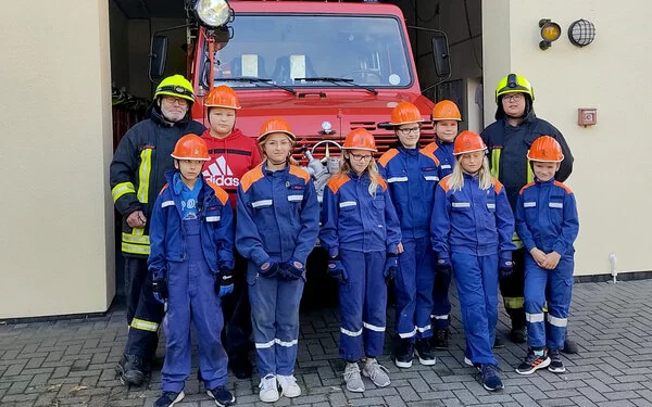 Nachwuchs der Freiwilligen Feuerwehr steht vor einem Feuerwehrauto.