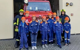 Nachwuchs der Freiwilligen Feuerwehr steht vor einem Feuerwehrauto.