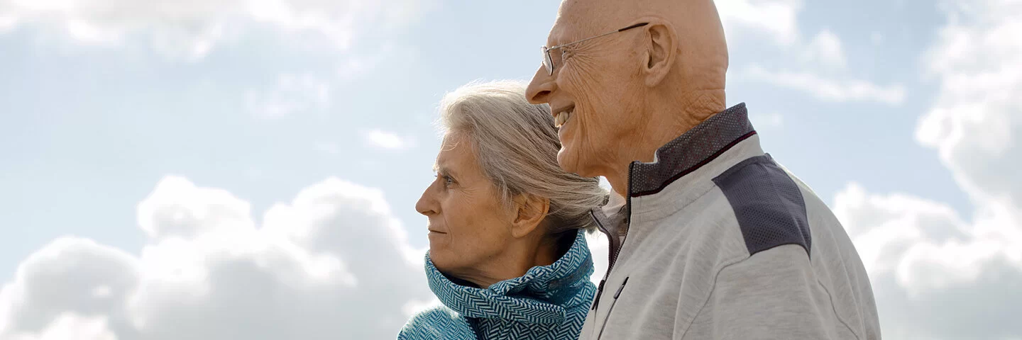 Zwei Senioren gehen draußen spazieren. Wie hoch ihr Beitrag zur Krankenversicherung ist, erfahren sie hier.