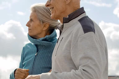 Zwei Senioren gehen draußen spazieren. Wie hoch ihr Beitrag zur Krankenversicherung ist, erfahren sie hier.