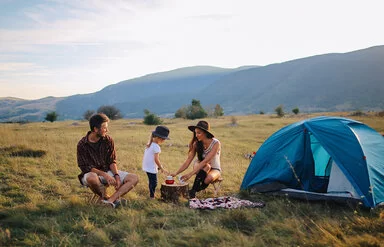 Zwei junge Menschen campen mit einem Kind in der Natur.