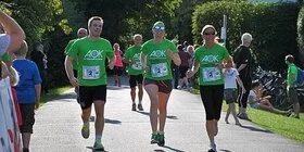 Mehrere Person mit grünen AOK-T-Shirts nehmen an einem Laufwettbewerb teil.