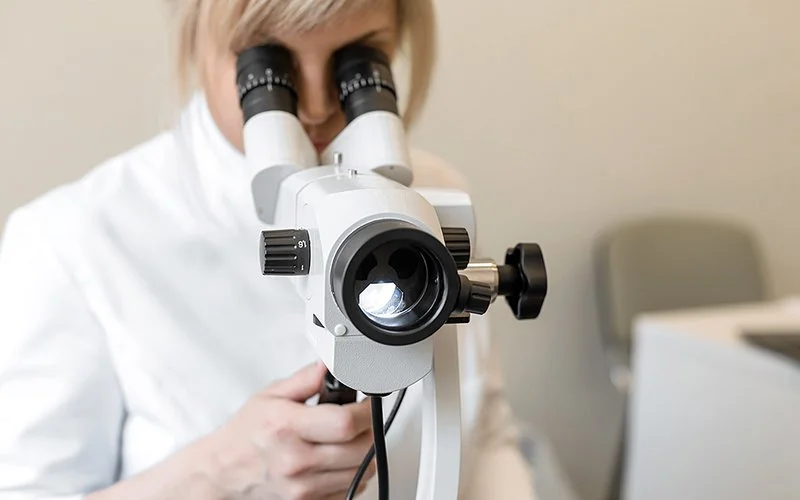 Eine Ärztin blickt durch ein Kolposkop.