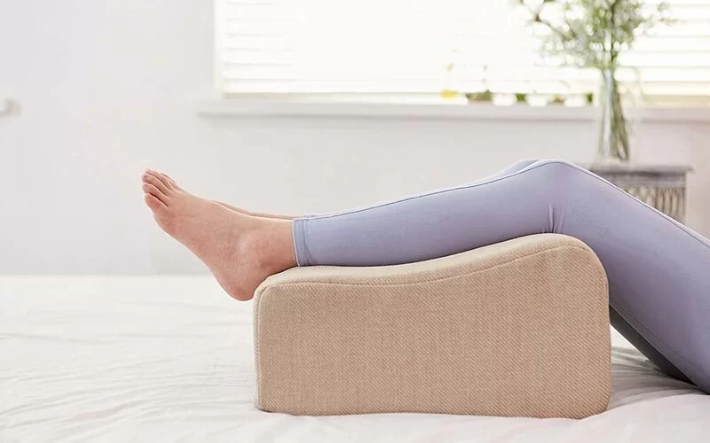 Die Beine einer weiblichen Person liegen auf einem Sitzkissen.