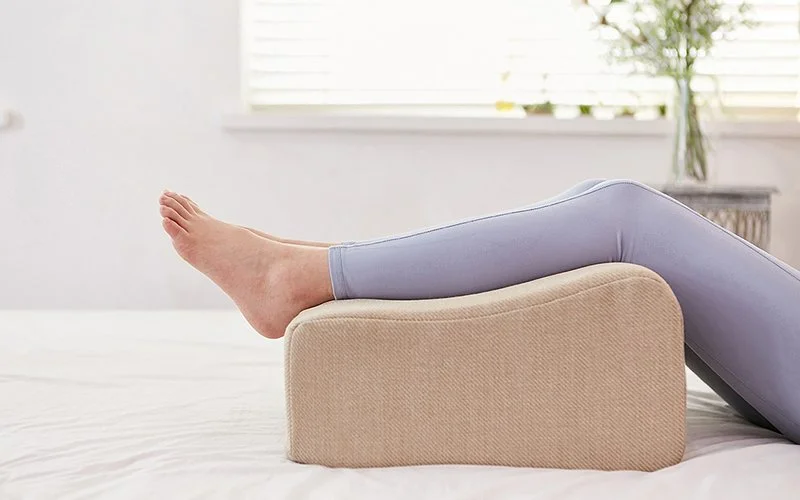 Die Beine einer weiblichen Person liegen auf einem Sitzkissen.