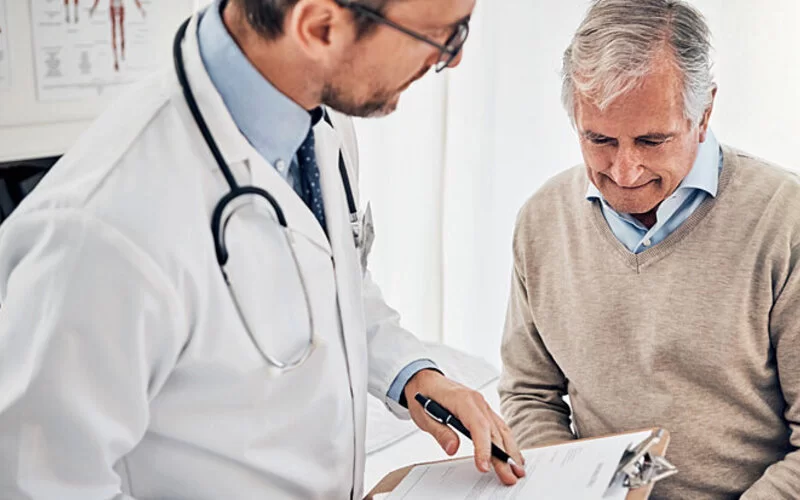 Ein Arzt erklärt einem Mann den Ablauf der Vorsorgeuntersuchung von Prostatakrebs.