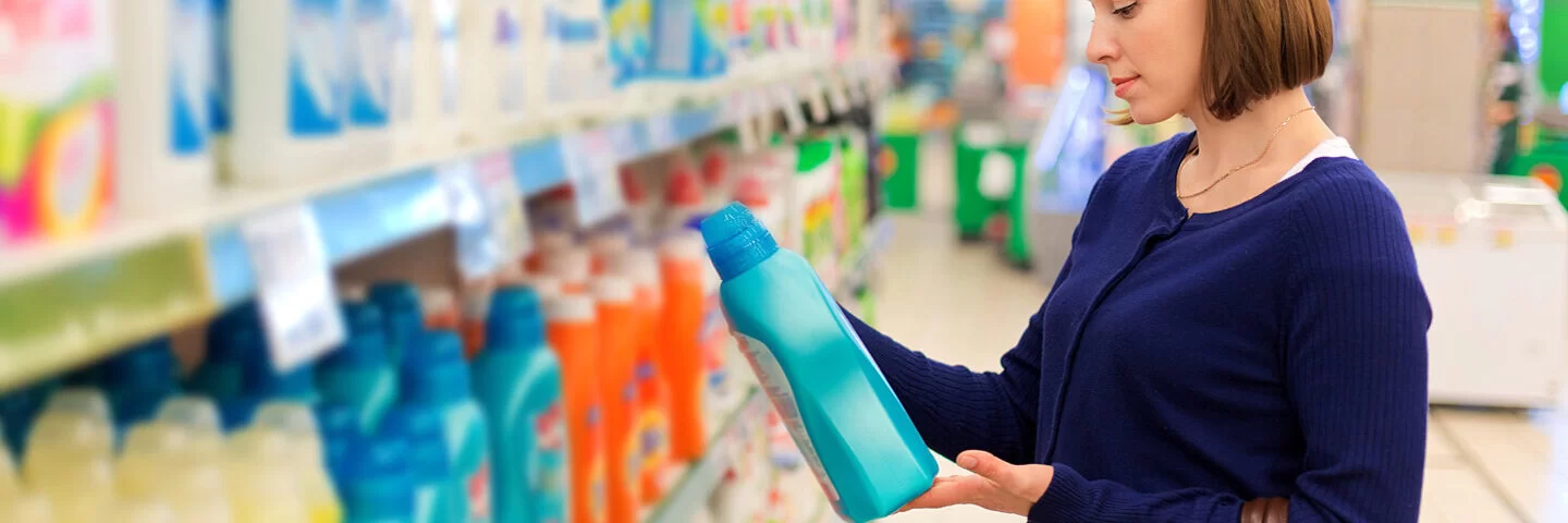 Eine Frau sucht im Supermarkt nach einem Waschmittel, das keine Allergie auslöst.