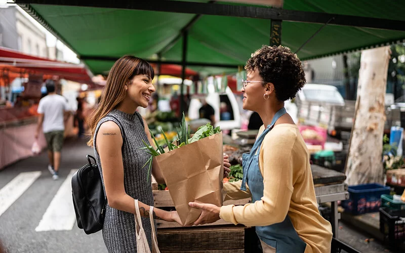 Eine Frau kauft Gemüse auf einem Wochenmarkt.