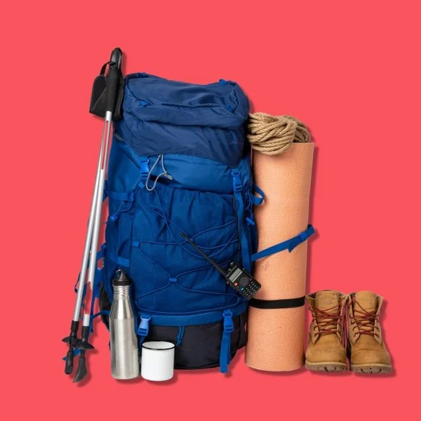 Zwei Wanderstöcke angelehnt an einen Rucksack, daneben stehen eine aufgerollte Matte und zwei Wanderstiefel.