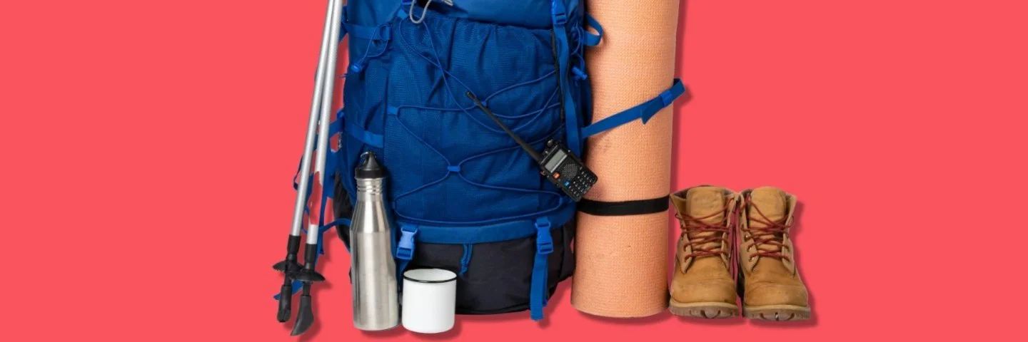 Zwei Wanderstöcke angelehnt an einen Rucksack, daneben stehen eine aufgerollte Matte und zwei Wanderstiefel.