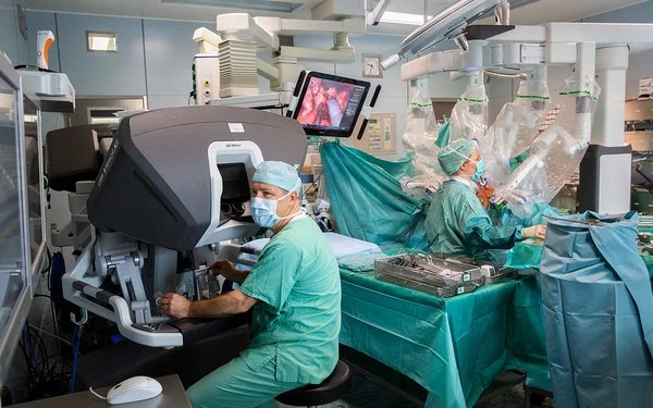 In einem Operationssaal des Universitätsklinikums Leipzig wird eine Operation mit einem Robotersystem durchgeführt. An der Bedienkonsole sitzt Prof. Dr. Jens-Uwe Stolzenburg.