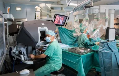 In einem Operationssaal des Universitätsklinikums Leipzig wird eine Operation mit einem Robotersystem durchgeführt. An der Bedienkonsole sitzt Prof. Dr. Jens-Uwe Stolzenburg.