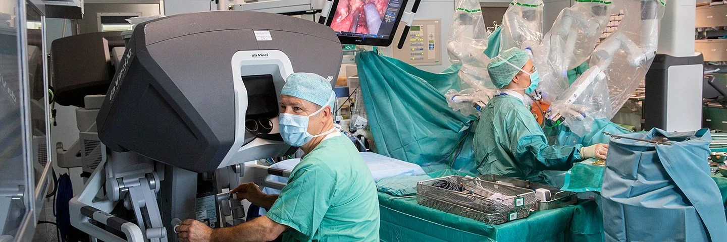 In einem Operationssaal des Universitätsklinikums Leipzig wird eine Operation mit einem Robotersystem durchgeführt. An der Bedienkonsole sitzt Prof. Dr. Jens-Uwe Stolzenburg.