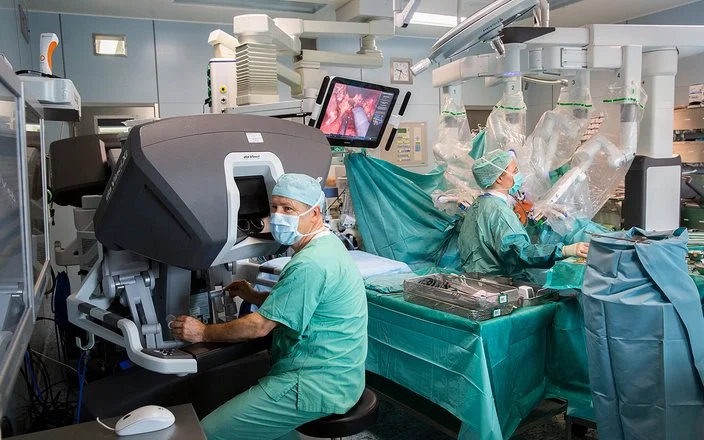 In einem Operationssaal des Universitätsklinikums Leipzig wird eine Operation mit einem Robotersystem durchgeführt. An der Bedienkonsole sitzt Prof. Dr. Jens-Uwe Stolzenburg.
