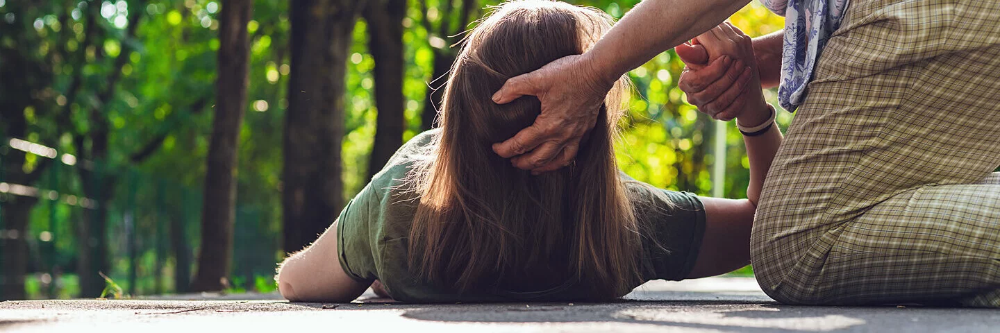 Frau hilft einer anderen Frau, die unter Synkope leidet.