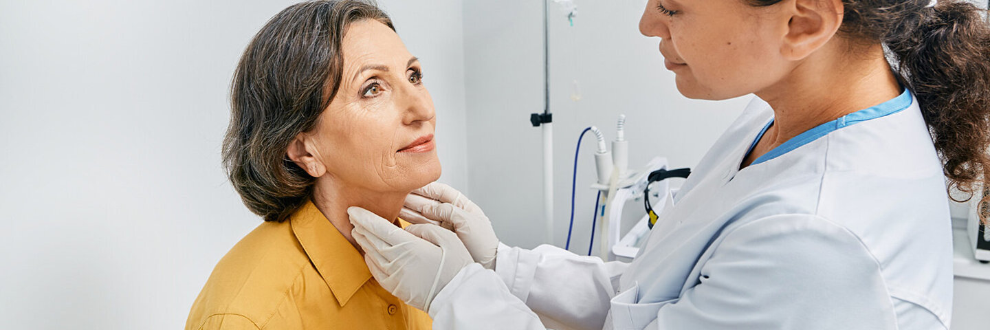 Ältere Frau leidet an Hashimoto-Thyreoiditis und lässt ihre Schilddrüse von einer Ärztin untersuchen.