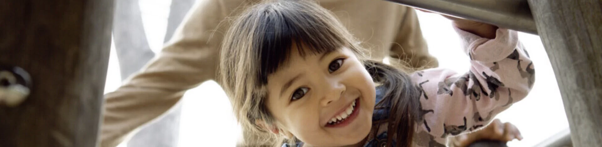 Ein Mädchen auf einem Klettergerüst. Ein Erwachsener steht hinter ihr. Mit der AOK Kinder-Krankenzusatzversicherung sind Kinder bestens abgesichert.