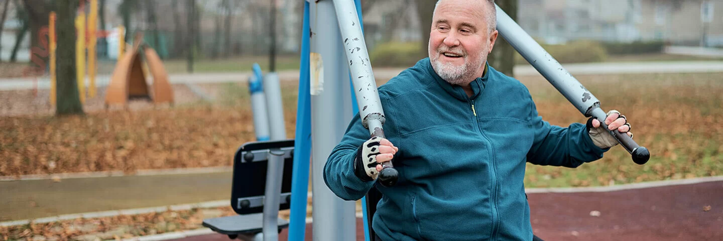 Ein Mann macht Sportübungen an Fitnessgeräten im Park.