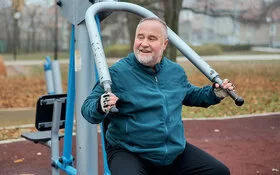 Ein Mann macht Sportübungen an Fitnessgeräten im Park.