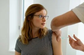 Eine Frau bekommt eine Schutzimpfung in den Oberarm injiziert.