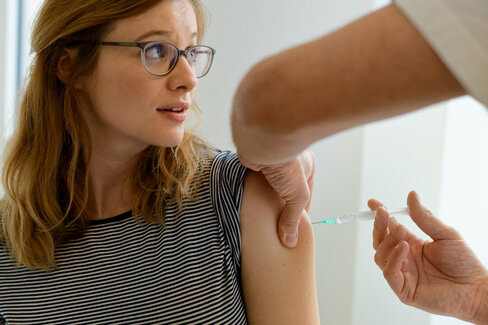 Eine Frau bekommt eine Schutzimpfung in den Oberarm injiziert.