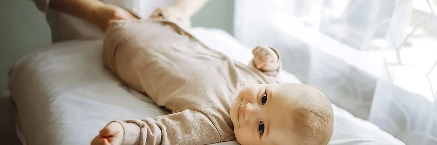 Baby liegt auf einer weichen Liege, während einer osteopathischen Behandlung.