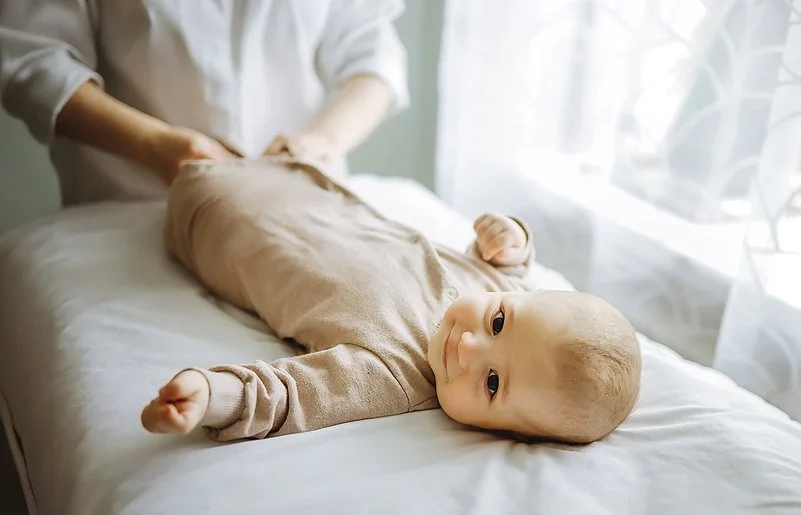 Baby liegt auf einer weichen Liege, während einer osteopathischen Behandlung.