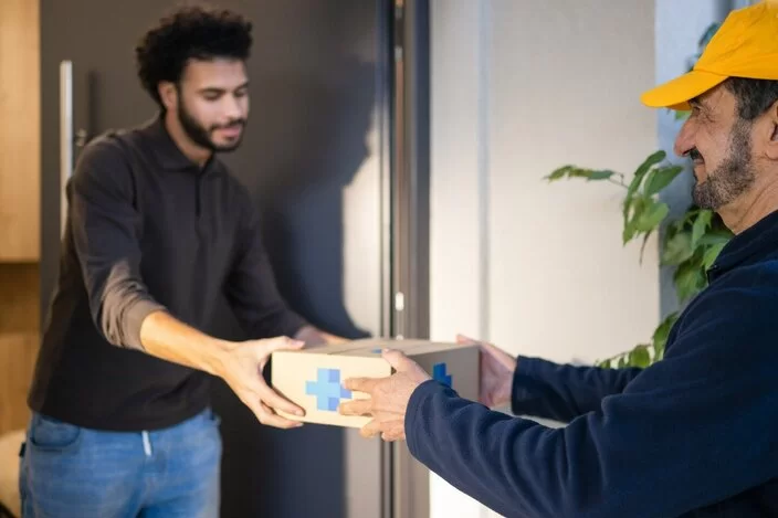 Ein Mann nimmt vom Paktboten eine Lieferung entgegen